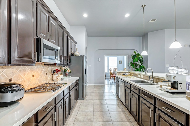 kitchen with stainless steel appliances, dark brown cabinets, sink, and pendant lighting