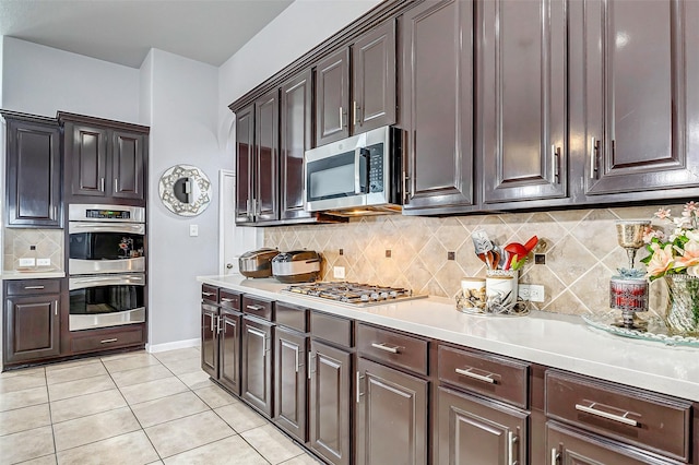 kitchen featuring stainless steel appliances, light tile patterned flooring, dark brown cabinets, and tasteful backsplash