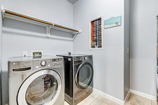 clothes washing area with independent washer and dryer and light tile patterned floors