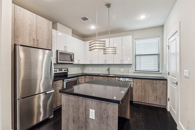 kitchen featuring dark wood-type flooring, sink, white cabinetry, appliances with stainless steel finishes, and a kitchen island