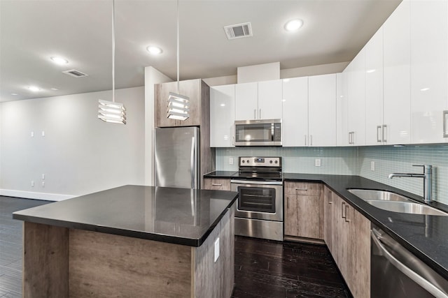 kitchen with stainless steel appliances, hanging light fixtures, sink, and white cabinets