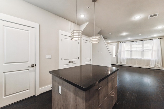 kitchen featuring pendant lighting, dark brown cabinetry, dark hardwood / wood-style flooring, and a center island