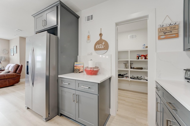 kitchen featuring gray cabinetry, stainless steel fridge with ice dispenser, and light wood-type flooring