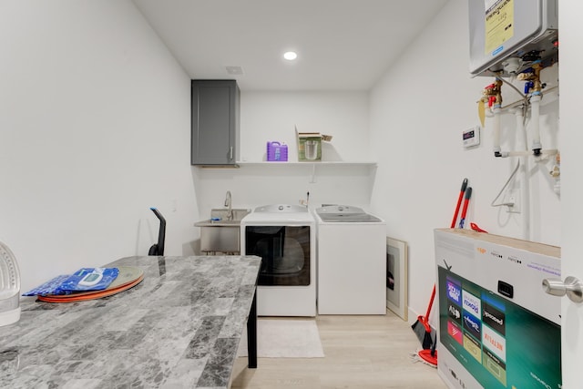 washroom featuring sink, cabinets, tankless water heater, independent washer and dryer, and light hardwood / wood-style floors