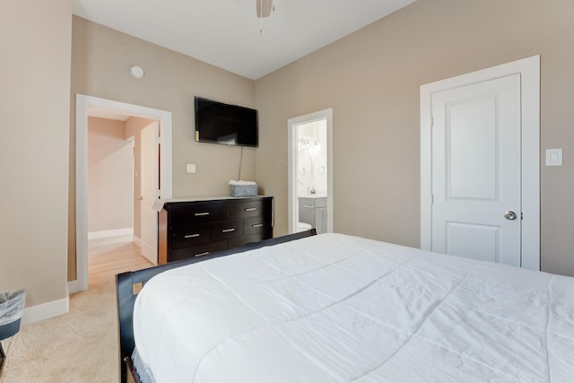 bedroom with ceiling fan, light colored carpet, and ensuite bath