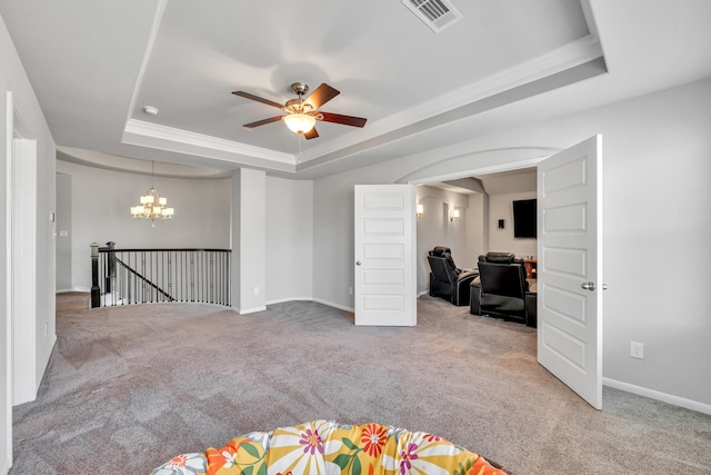 carpeted spare room with a raised ceiling, ornamental molding, and ceiling fan with notable chandelier