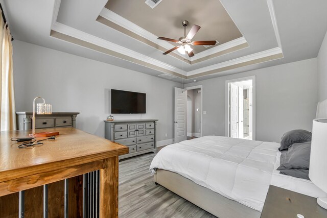 bedroom featuring ornamental molding, light hardwood / wood-style floors, a raised ceiling, and ceiling fan