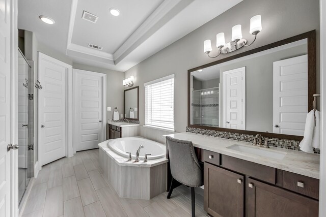 bathroom featuring vanity, shower with separate bathtub, and a tray ceiling