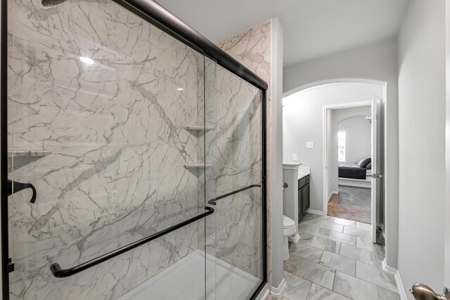 bathroom featuring a shower with door, vanity, and toilet