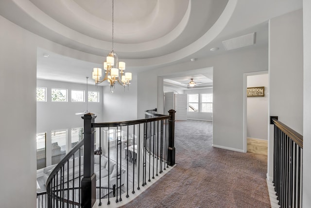 hall featuring a notable chandelier, a tray ceiling, and carpet