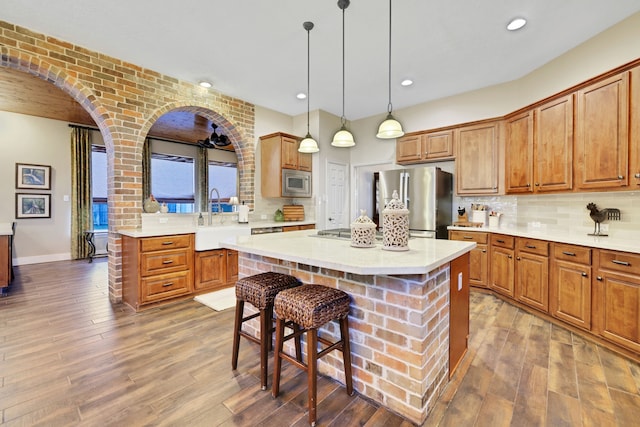 kitchen featuring appliances with stainless steel finishes, wood-type flooring, sink, a breakfast bar area, and a center island