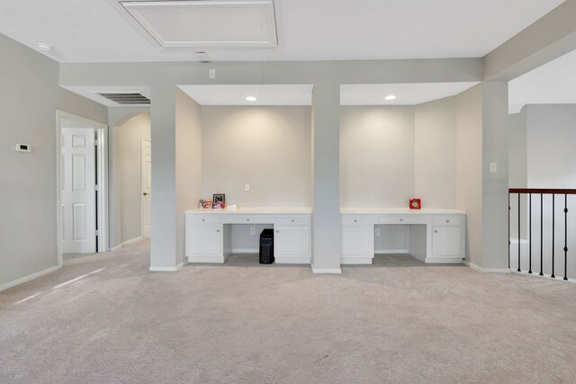 interior space featuring built in desk and light colored carpet