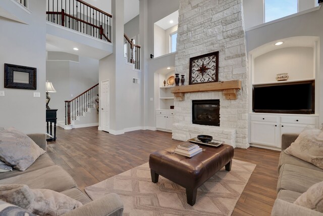 living room featuring built in shelves, hardwood / wood-style floors, and a high ceiling