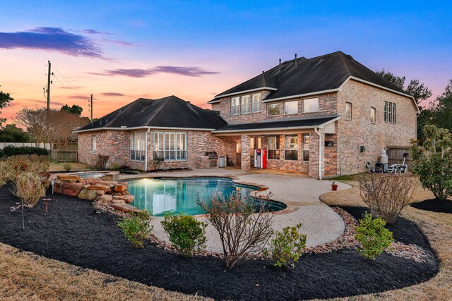 back house at dusk with a pool with hot tub and a patio area