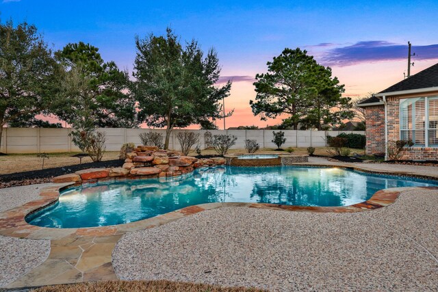 pool at dusk with a patio and an in ground hot tub