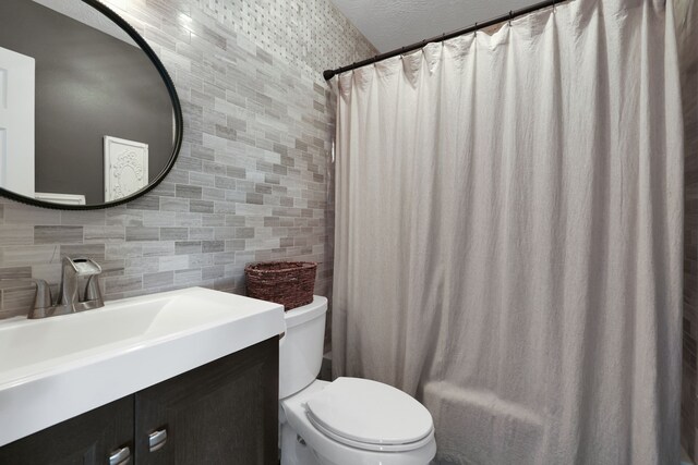 bathroom featuring vanity, tile walls, decorative backsplash, and toilet