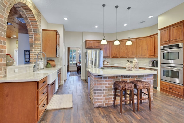 kitchen with pendant lighting, sink, appliances with stainless steel finishes, a kitchen breakfast bar, and kitchen peninsula