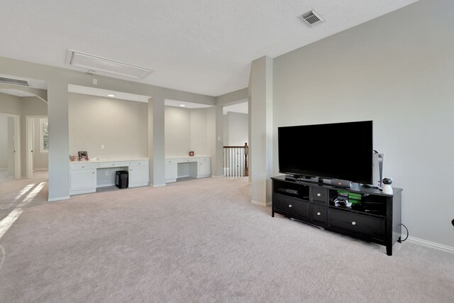 carpeted living room featuring built in desk and a textured ceiling