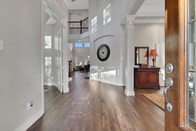 entryway featuring decorative columns, dark hardwood / wood-style floors, and a high ceiling