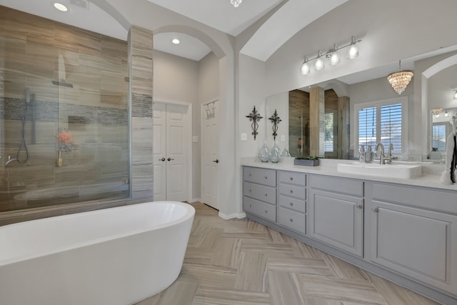 bathroom with vanity, a notable chandelier, parquet flooring, and plus walk in shower