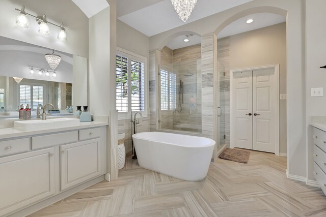 bathroom featuring parquet floors, vanity, a chandelier, and independent shower and bath