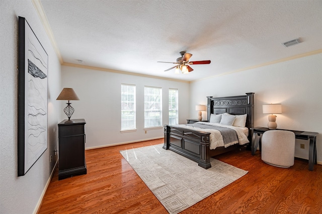 bedroom with wood-type flooring, ornamental molding, ceiling fan, and a textured ceiling