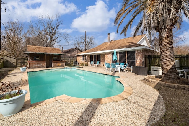 view of swimming pool featuring outdoor dry bar, a fenced in pool, a fenced backyard, a patio area, and an outbuilding