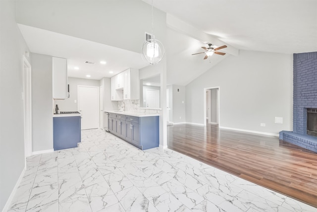 kitchen featuring sink, ceiling fan, white cabinetry, a brick fireplace, and decorative light fixtures