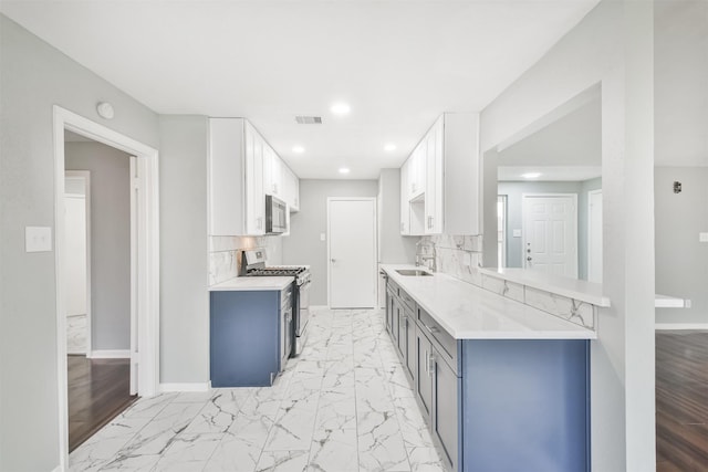 kitchen with stainless steel appliances, sink, decorative backsplash, and white cabinets