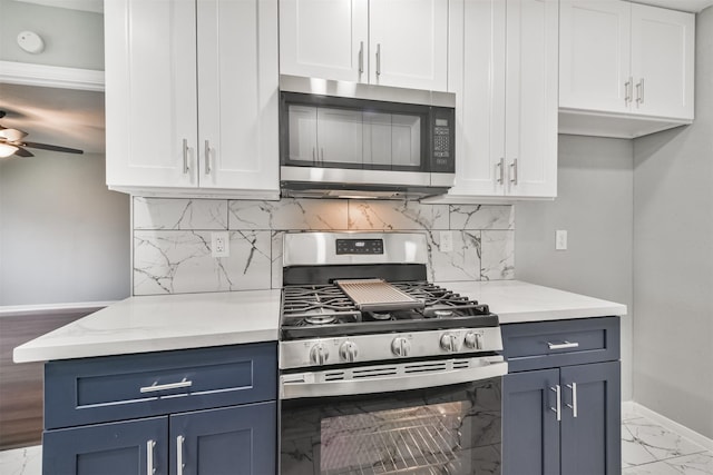 kitchen with ceiling fan, stainless steel appliances, white cabinets, and blue cabinetry