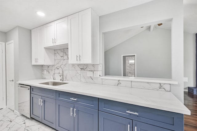 kitchen with tasteful backsplash, sink, white cabinets, stainless steel dishwasher, and light stone counters