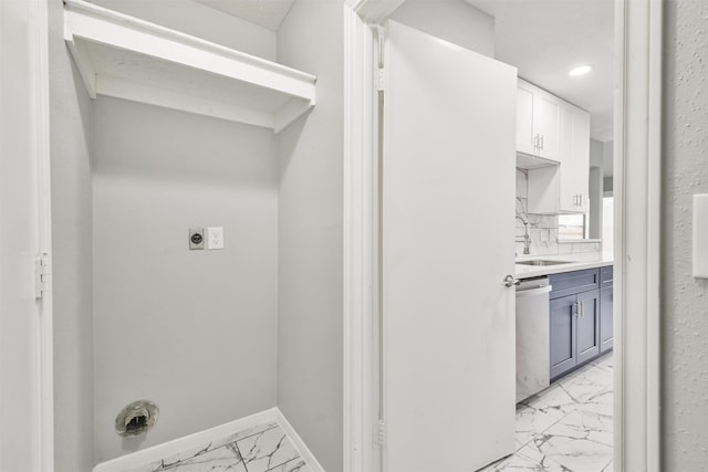 clothes washing area with white cabinetry and sink