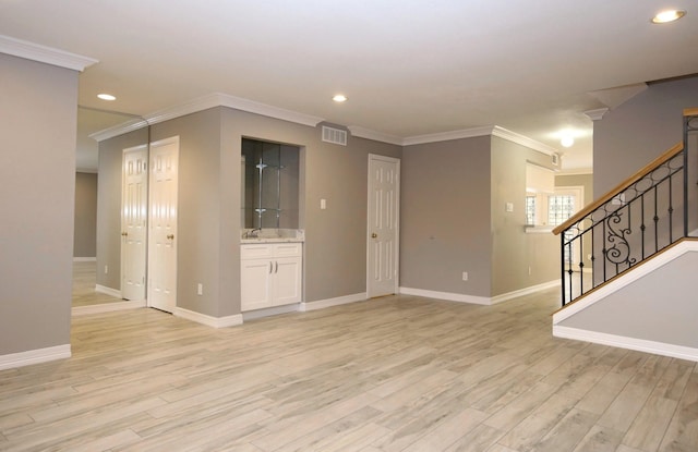 unfurnished living room with ornamental molding, sink, and light wood-type flooring