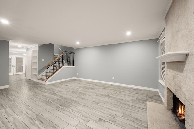 unfurnished living room featuring a brick fireplace, crown molding, and light hardwood / wood-style floors