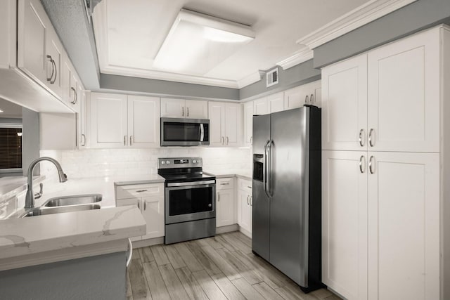 kitchen featuring sink, white cabinetry, light stone counters, stainless steel appliances, and backsplash