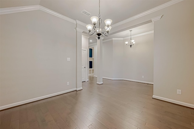 empty room with an inviting chandelier, hardwood / wood-style floors, and ornamental molding