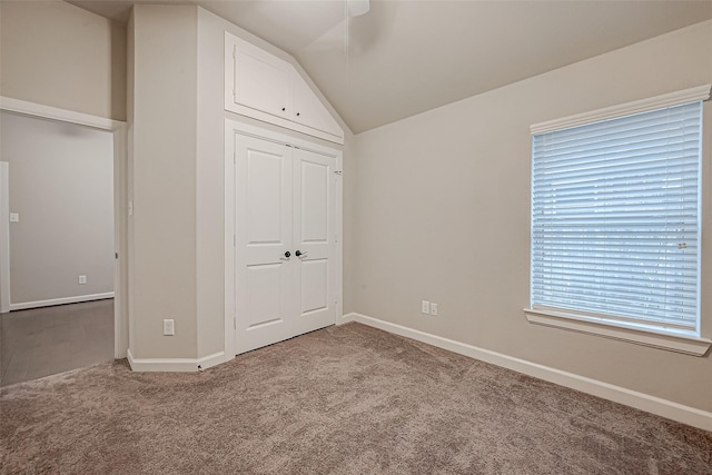 unfurnished bedroom with carpet floors, a closet, and vaulted ceiling