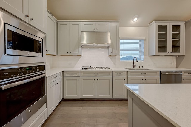 kitchen featuring sink, white cabinetry, appliances with stainless steel finishes, light stone countertops, and decorative backsplash