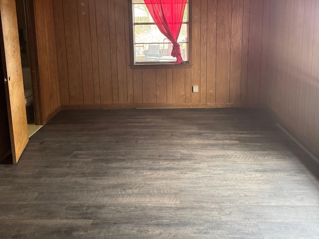 spare room featuring dark hardwood / wood-style floors and wooden walls