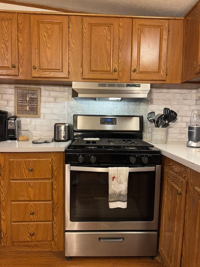 kitchen with wood-type flooring, stainless steel gas range, and backsplash