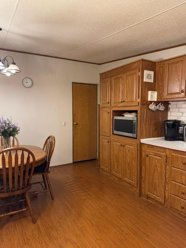 kitchen featuring crown molding, a textured ceiling, and light hardwood / wood-style flooring