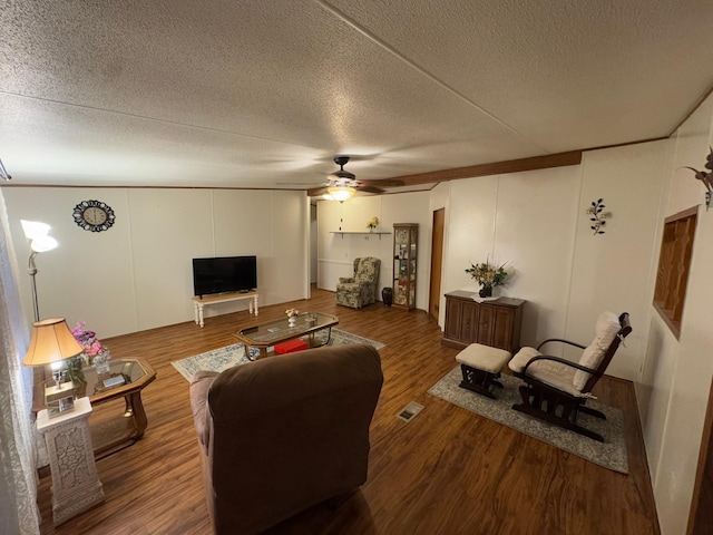 living room featuring ceiling fan, a textured ceiling, and dark hardwood / wood-style flooring