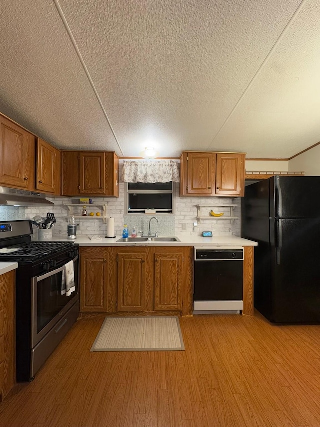 kitchen featuring decorative backsplash, sink, light hardwood / wood-style flooring, and black appliances