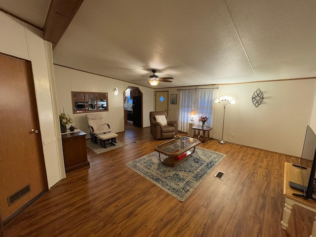 living room featuring ceiling fan, dark wood-type flooring, a textured ceiling, and vaulted ceiling