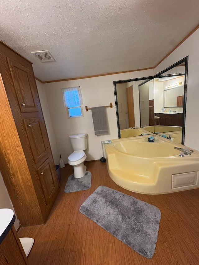 bathroom with toilet, crown molding, a textured ceiling, vanity, and hardwood / wood-style flooring