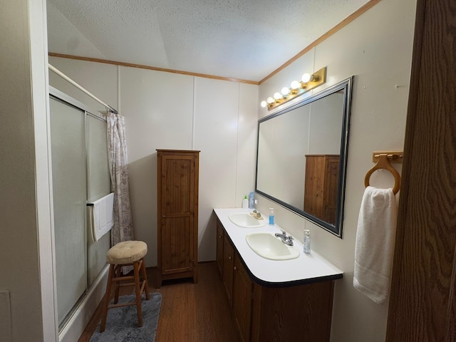 bathroom featuring wood-type flooring, a textured ceiling, crown molding, and vanity