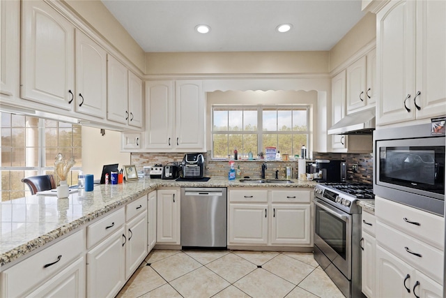 kitchen with white cabinetry, stainless steel appliances, light stone countertops, and sink