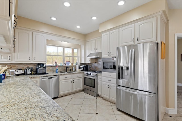 kitchen with light tile patterned flooring, sink, white cabinetry, stainless steel appliances, and decorative backsplash