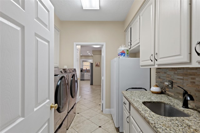 laundry area featuring sink, cabinets, a textured ceiling, light tile patterned floors, and washing machine and dryer