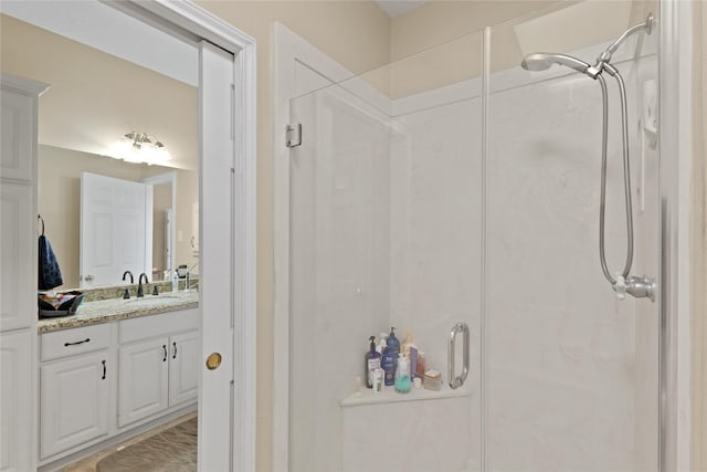 bathroom featuring a shower with door and vanity